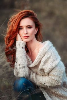 Woman with red hair wearing a chunky knit sweater and jeans outdoors