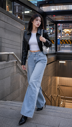 Woman in a black leather jacket and wide leg jeans walking down city stairs