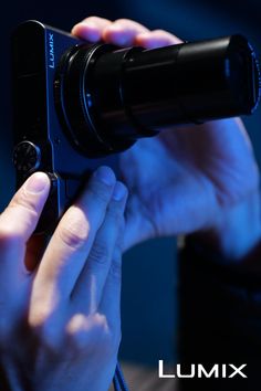 Hands holding a digital camera under blue lighting
