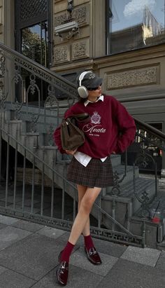 Person in a plaid skirt and burgundy sweatshirt with headphones outdoors