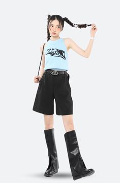 Woman with pigtails wearing a light blue top, black shorts, and black boots