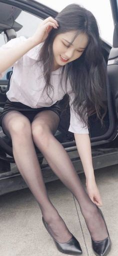 Woman in a white shirt and black skirt getting out of a car