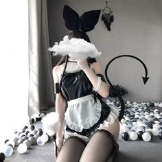 Person in a maid costume with bunny ears and a devil tail kneeling in a ball pit