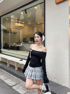 Woman in an off-shoulder top and plaid skirt posing outdoors