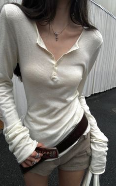 Woman in a white long sleeve shirt and short shorts with a brown belt