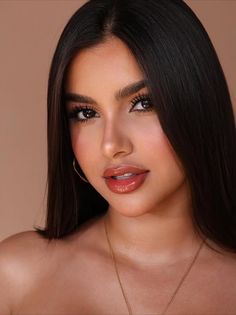 Woman with long dark hair and glossy lips wearing hoop earrings and a gold necklace