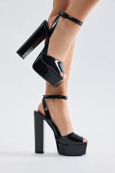 Woman's legs wearing black patent leather platform heels with ankle straps