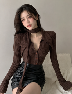 Woman with long hair wearing a brown top and black skirt indoors