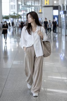 Woman in a white shirt and wide leg pants walking through an airport