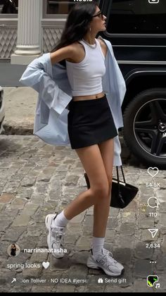 Woman in a black mini skirt and white crop top on a cobblestone street