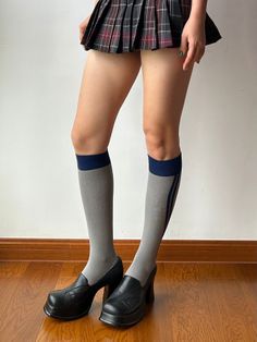 Person wearing a plaid skirt, knee-high socks, and platform heels indoors