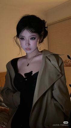Woman with an updo and trench coat over a black top, indoors