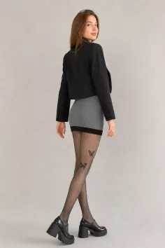 Woman in a black cropped jacket and grey mini skirt with butterfly tights
