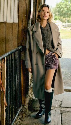 Woman in a long coat, plaid shorts, and black boots outdoors