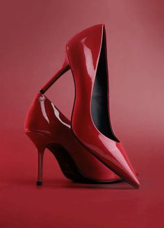 Two red patent leather high heels on a matching red background