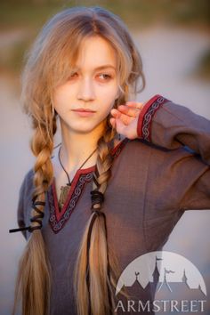 Young woman with blonde braids in a medieval-style dress outdoors