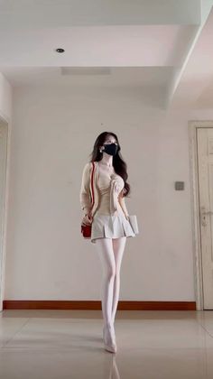 Woman in a pleated skirt and white tights posing indoors