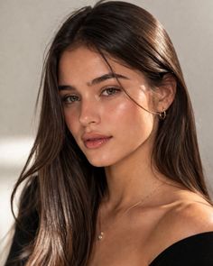 Woman with long dark hair wearing an off-shoulder top and jewelry
