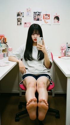 Woman with long black hair taking a selfie while sitting at a desk indoors