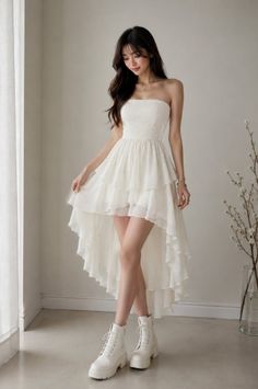 Woman in a white strapless high-low dress and white boots indoors