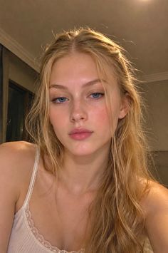 Blonde woman with blue eyes wearing a white camisole with lace trim