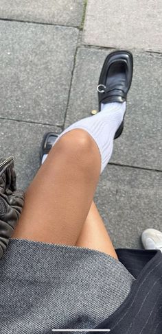 Person wearing black loafers, white socks, and a short skirt outdoors
