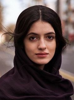 Woman with dark hair and a headscarf looking directly at the camera