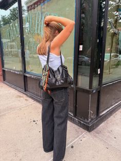 Woman in a white tank top and black jeans on a street during the day