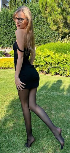 Woman in a black dress and tights posing in a garden