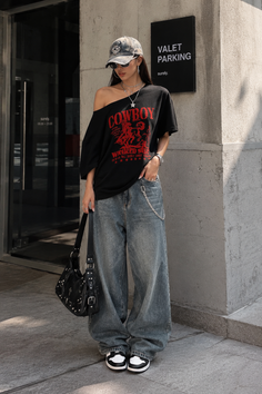 Woman in an oversized t-shirt and baggy jeans with a baseball cap and sunglasses