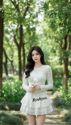 Woman in a white dress holding a flower in a forest
