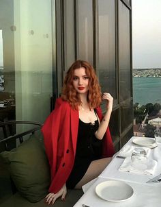 Woman with red hair in a red blazer and black dress at a rooftop restaurant