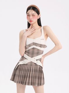 Woman with long black hair and a headband wearing a plaid dress, winking