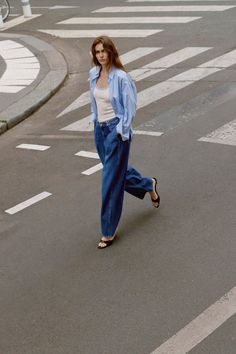 Woman in a striped shirt and loose jeans walking on a street