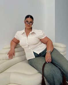 Woman in a striped shirt and jeans sitting on a white couch