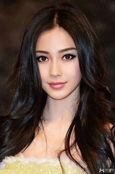 Woman with long black hair and a glitter dress against a dark background