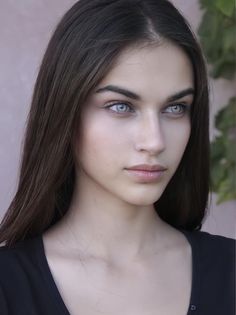 Woman with long brown hair and blue eyes in a close-up outdoor portrait