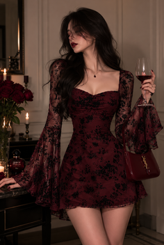 Woman in a red lace dress holding a wine glass in a dimly lit room