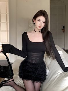 Woman in a black sheer top and fuzzy mini skirt posing indoors