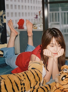 Woman in a red shirt and blue pants lying down with tiger plushies