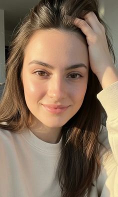 Woman with long brown hair in a white sweatshirt, smiling at the camera
