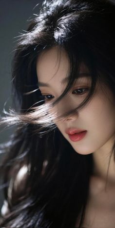 Woman with long black hair illuminated by backlight, looking down