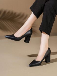 Person wearing black pointed-toe block heels and black pants indoors
