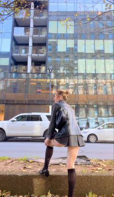 Woman in a leather jacket and pleated skirt on an urban street