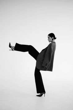 Woman in a suit jacket and black pants posing in a studio