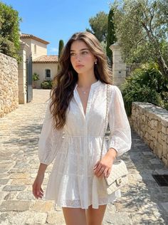 Woman in a white dress walking on a cobblestone street on a sunny day