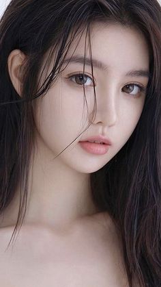 Woman with long dark wet hair and exposed shoulders looking at the viewer