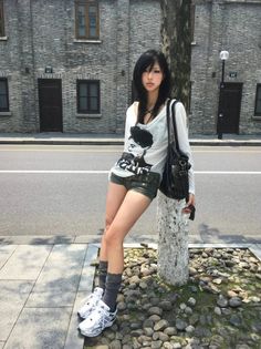 Woman with long black hair wearing short shorts and a white shirt on a street