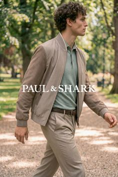 Man with curly hair wearing a bomber jacket and polo shirt walking outdoors