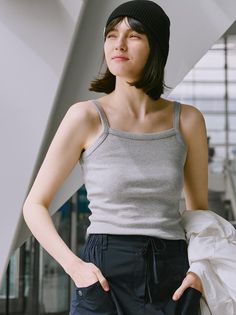 Woman in a black beanie and gray tank top looking away outdoors